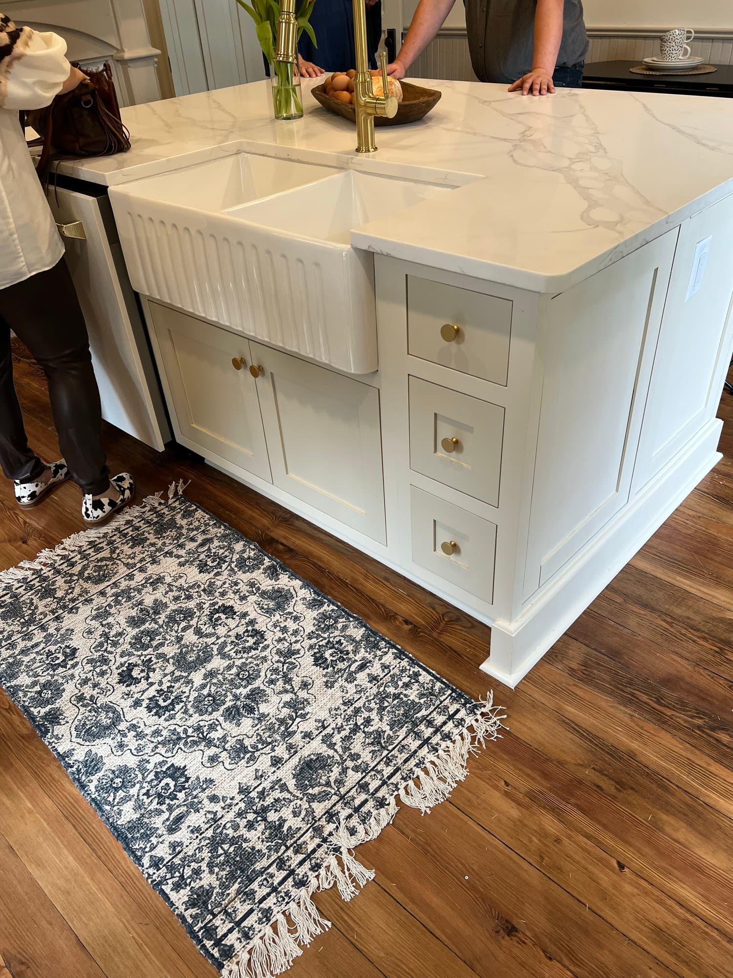 Inset island cabinetry with a fluted farmhouse sink, brass knobs, and flush drawer fronts